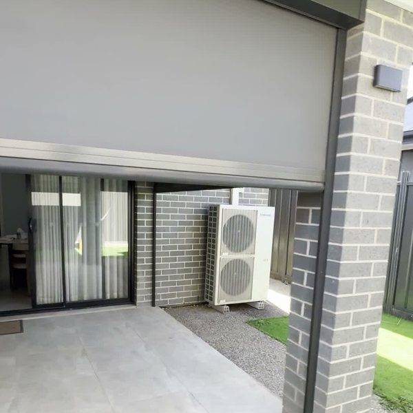 A track-guided outdoor blind lowering over a rear alfresco