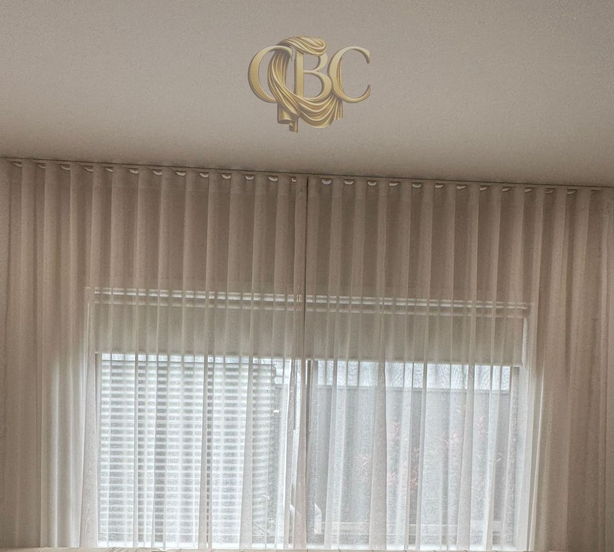 Sheer curtains layered over venetian blinds for day and night control